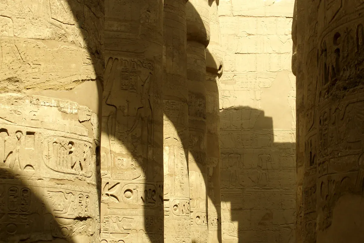 Sunlit columns and carved hieroglyphs in the Great Hypostyle Hall at Karnak, seen on a Valley of the Kings tour